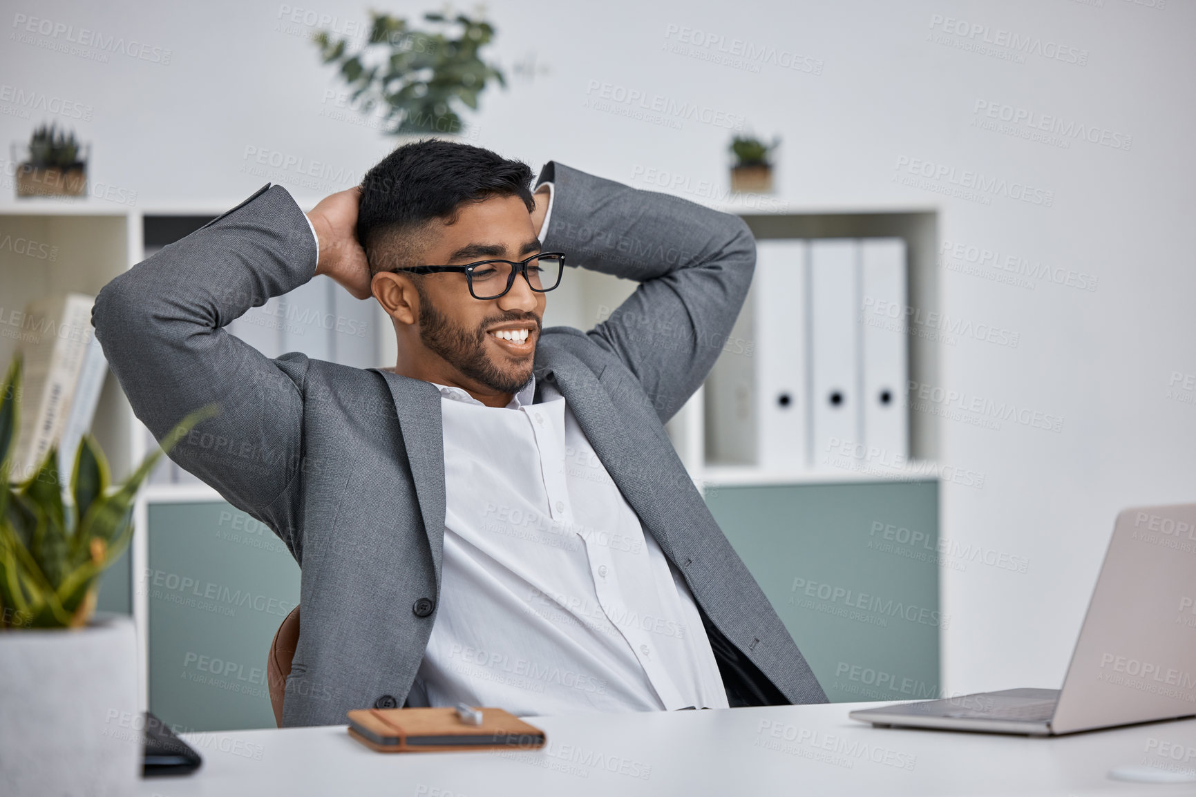 Buy stock photo Shot of a young businessman sitting with his hands behind his head in an office