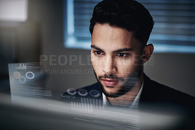 Buy stock photo Shot of a handsome young businessman sitting alone in the office at night and using his computer