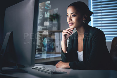 Buy stock photo Shot of an attractive young businesswoman sitting alone in the office at night and looking contemplative while using her computer