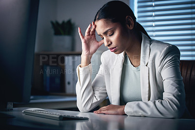 Buy stock photo Shot of an attractive young businesswoman sitting alone in the office at night and feeling stressed