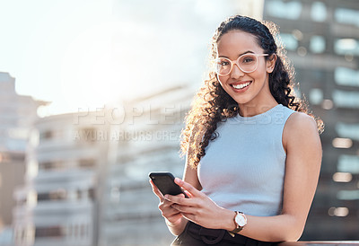 Buy stock photo Shot of an attractive young businesswoman standing alone outside and using her cellphone
