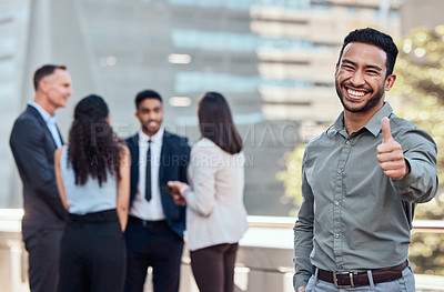 Buy stock photo Shot of a handsome young businessman standing outside and showing a thumbs up while his colleagues standing behind him