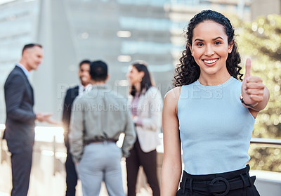 Buy stock photo Shot of an attractive young businesswoman standing outside and showing a thumbs up while her colleagues standing behind her