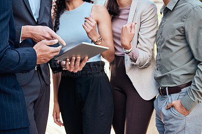 Buy stock photo Cropped shot of an unrecognizable group of businesspeople standing outside together and using a digital tablet