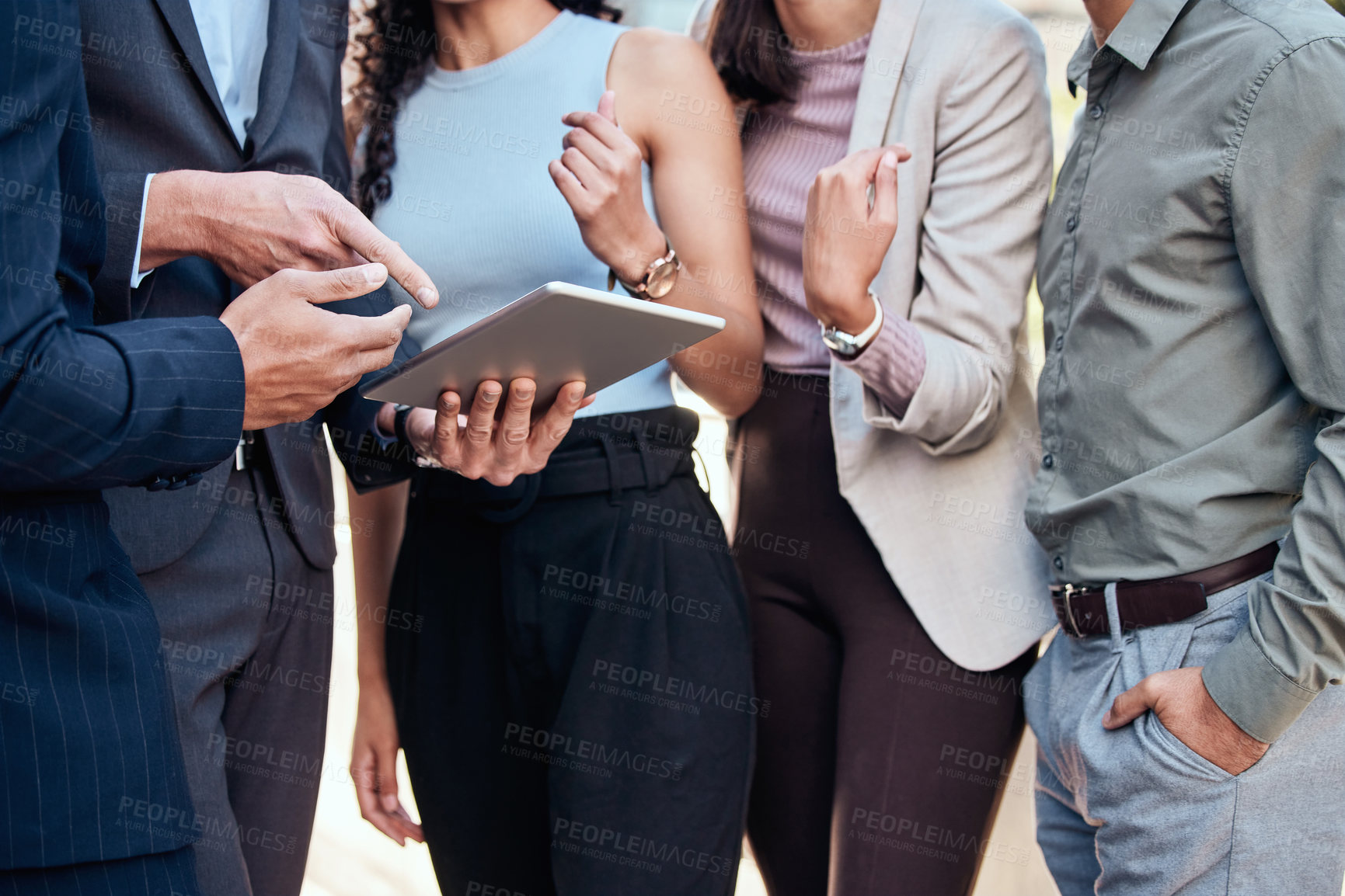 Buy stock photo Cropped shot of an unrecognizable group of businesspeople standing outside together and using a digital tablet