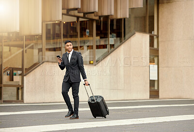 Buy stock photo Shot of a businessman walking around town with his luggage using his smartphone