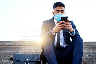 Buy stock photo Shot of a young businessman sitting on steps using his smartphone