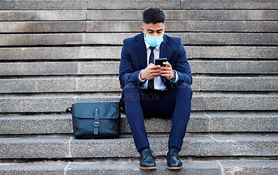 Buy stock photo Shot of a young businessman sitting on steps using his smartphone