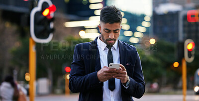Buy stock photo Shot of a handsome young businessman walking around town using his smartphone
