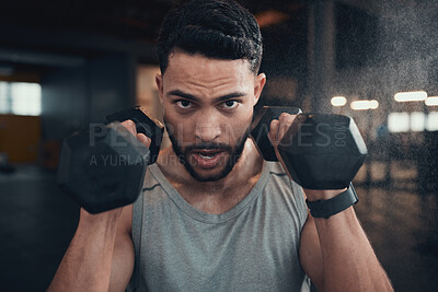 Buy stock photo Shot of a young man using weights in the gym