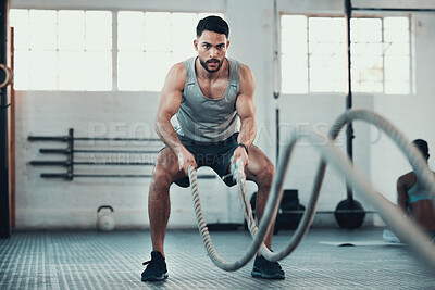 Buy stock photo Shot of a young man using the ropes in the gym to build arm strength