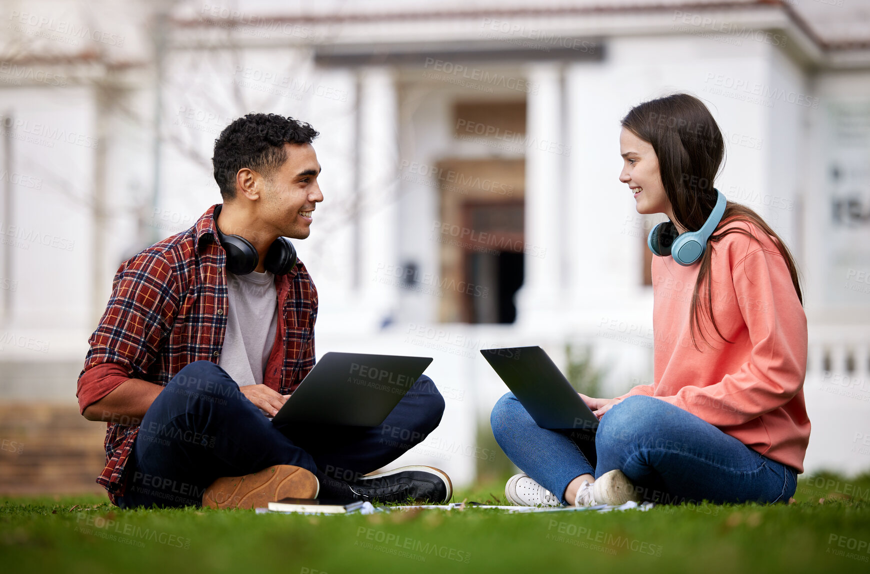 Buy stock photo Shot of two students using their laptops while sitting outside on campus