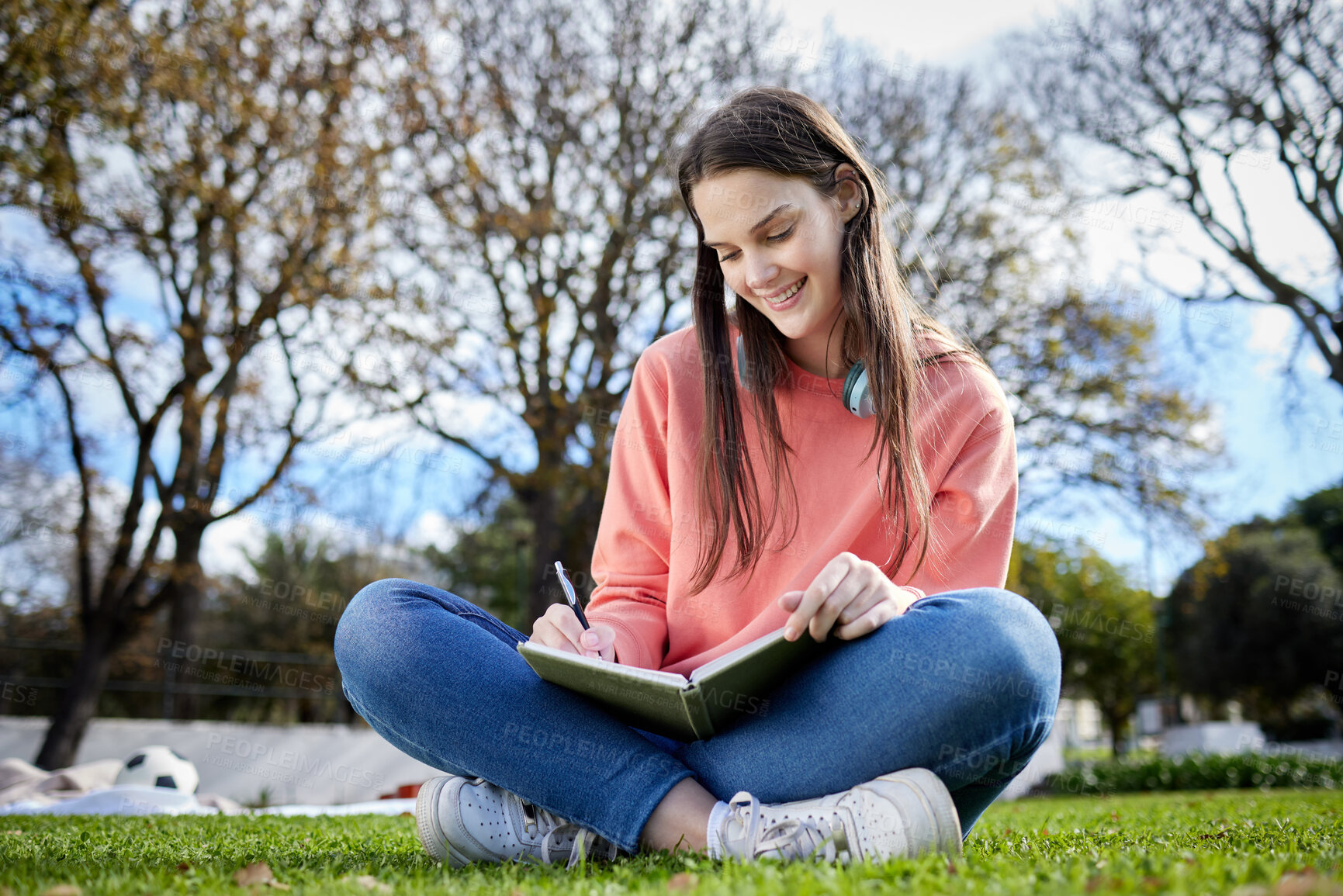 Buy stock photo Shot of a student writing in her notebook while sitting outside