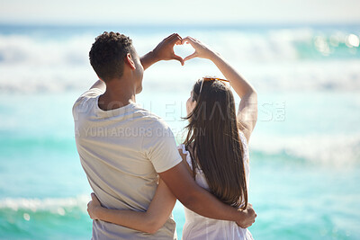 Buy stock photo Shot of a young couple making a heart gesture with their hands at the beach