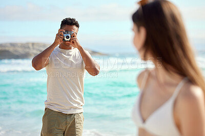 Buy stock photo Shot of a young man taking pictures of his girlfriend at the beach