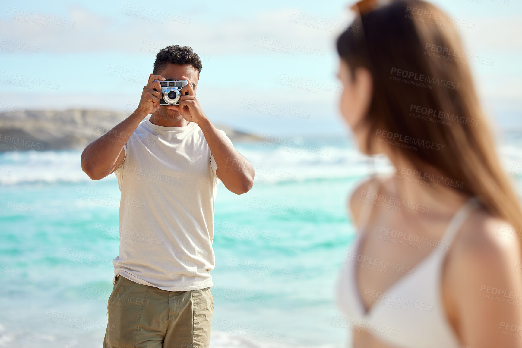 Buy stock photo Shot of a young man taking pictures of his girlfriend at the beach