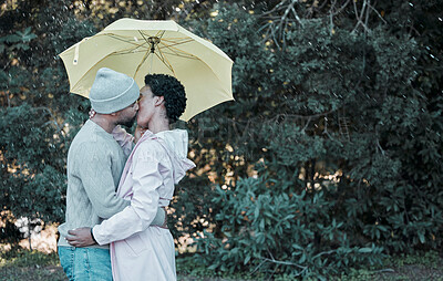 Buy stock photo Shot of a young couple kissing while standing under an umbrella