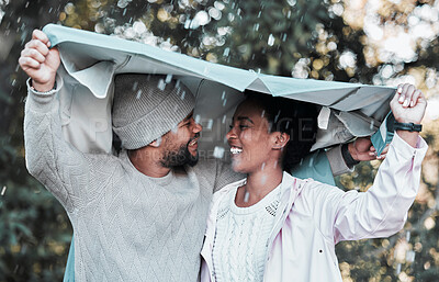 Buy stock photo Shot of a young couple holding a jacket over their heads while out in the rain