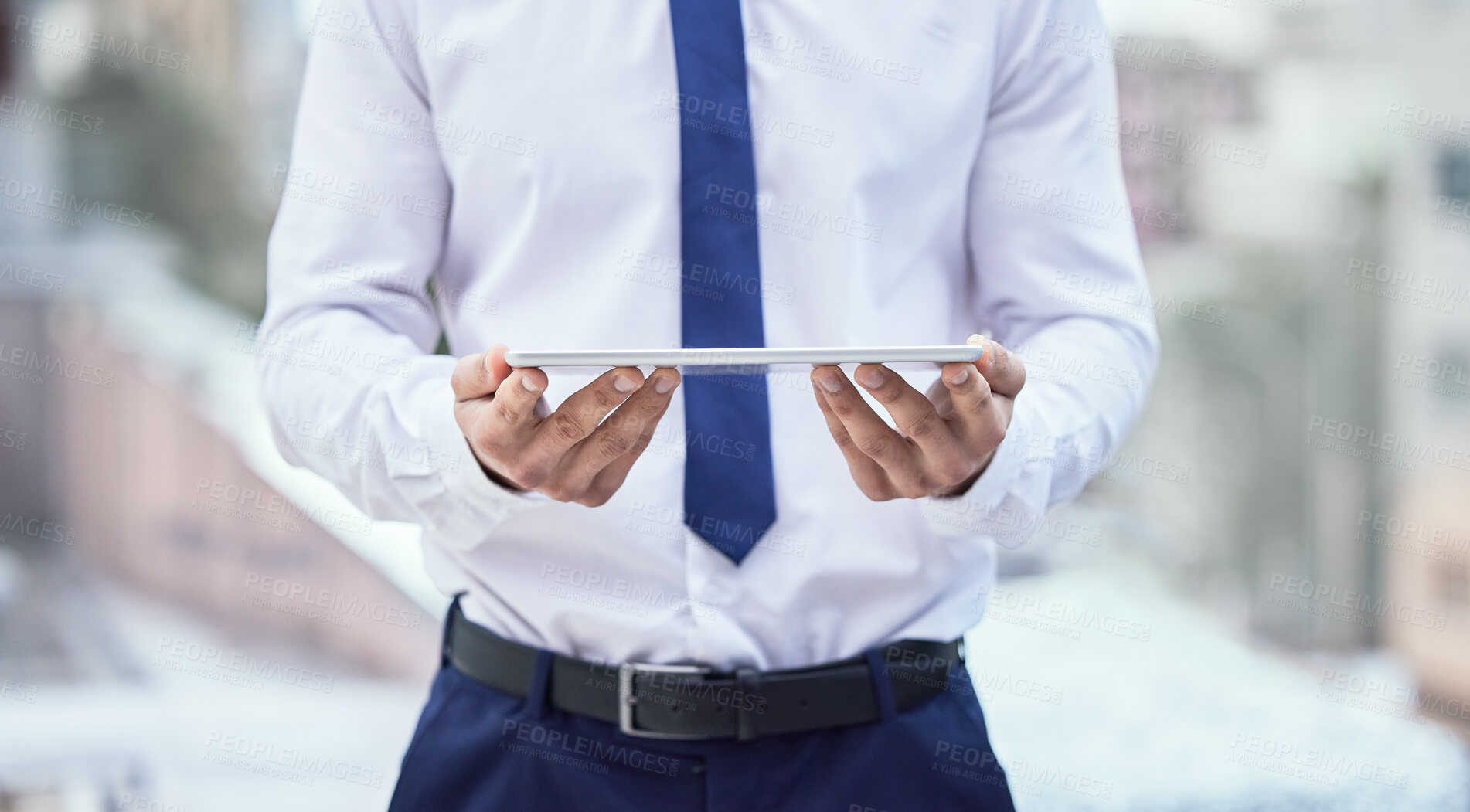 Buy stock photo Cropped shot of an unrecognizable businessman holding his tablet while standing outside in the city