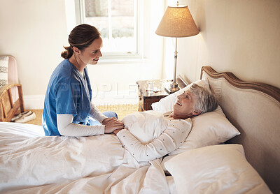 Buy stock photo Shot of a young nurse chatting with a senior woman in bed at a retirement home