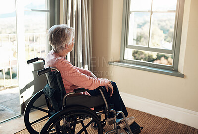 Buy stock photo Shot of a senior woman in a wheelchair looking thoughtfully out of a window at home