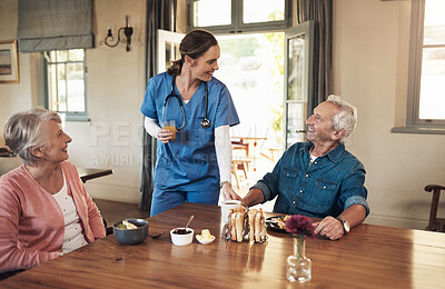 Buy stock photo Shot of a young nurse checking up on a senior couple during breakfast at a nursing home