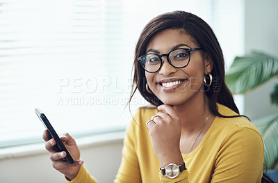Buy stock photo Shot of an attractive young woman sitting alone at home and using her cellphone