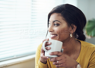 Buy stock photo Shot of an attractive young woman sitting alone at home and drinking a cup of coffee