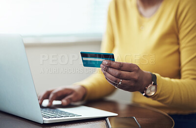Buy stock photo Cropped shot of an unrecognizable woman sitting alone at home and using her laptop for online shopping