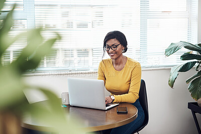 Buy stock photo Shot of an attractive young woman sitting alone at home and using her laptop