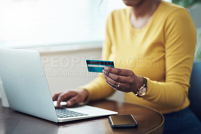 Buy stock photo Cropped shot of an unrecognizable woman sitting alone at home and using her laptop for online shopping