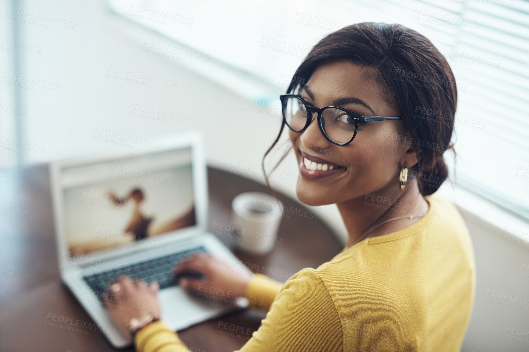 Buy stock photo Shot of an attractive young woman sitting alone at home and using her laptop