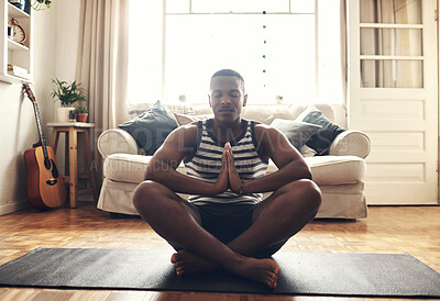 Buy stock photo Shot of a sporty young man meditating at home