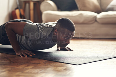 Buy stock photo Shot of a sporty young man doing push up exercises at home