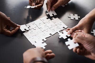 Buy stock photo Closeup shot of a group of unrecognisable businesspeople joining puzzle pieces together in an office