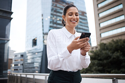 Buy stock photo Shot of a young businesswoman using a cellphone while standing on a balcony outside an office