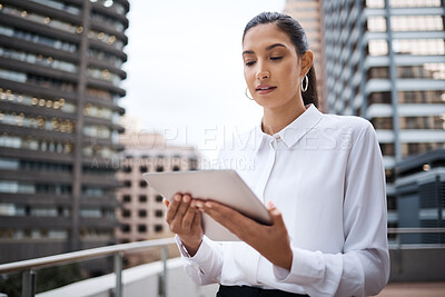 Buy stock photo Shot of a young businesswoman using a digital tablet while standing on a balcony outside an office