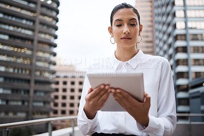 Buy stock photo Shot of a young businesswoman using a digital tablet while standing on a balcony outside an office