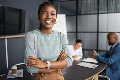 Buy stock photo Portrait of a young businesswoman standing with her arms crossed in a boardroom with her colleagues in the background