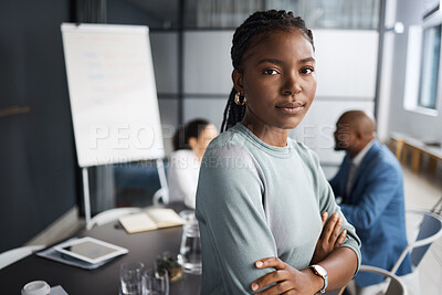 Buy stock photo Portrait of a young businesswoman standing with her arms crossed in a boardroom with her colleagues in the background