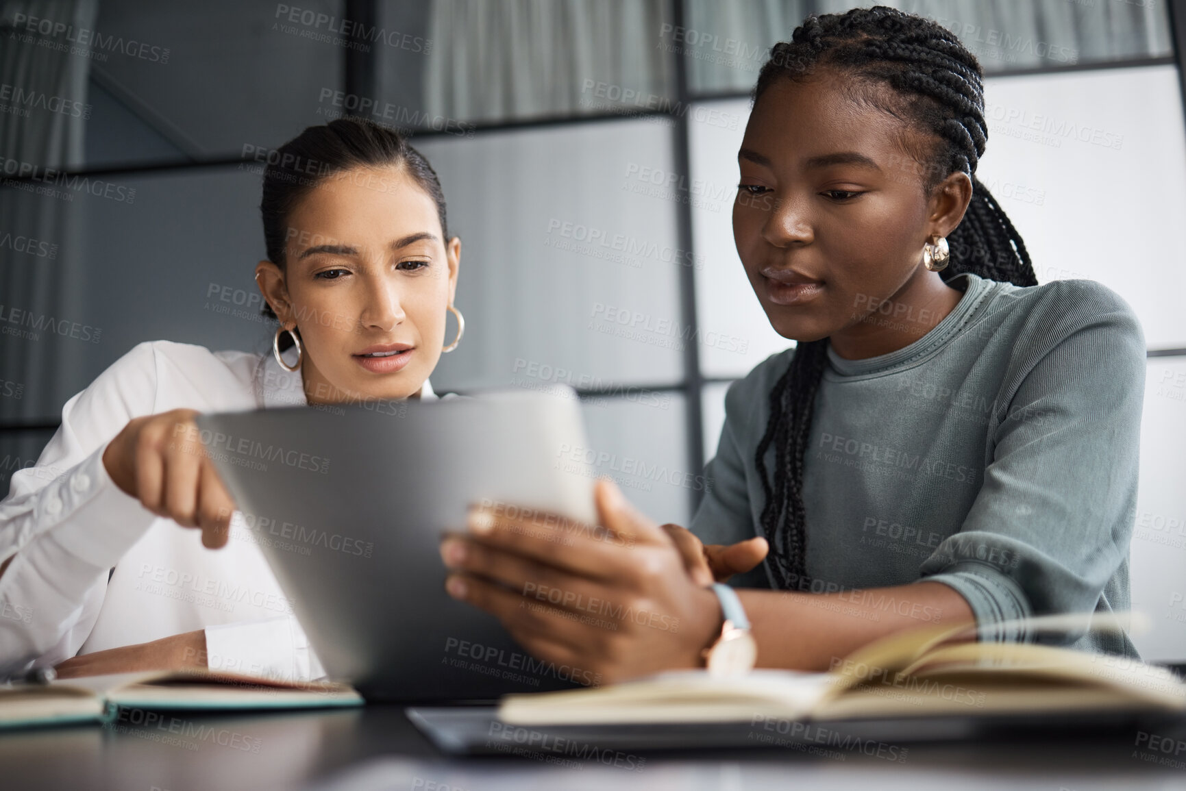 Buy stock photo Shot of two businesswomen working together on a digital tablet in an office