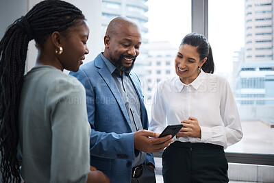 Buy stock photo Shot of a group of businesspeople using a cellphone together in an office