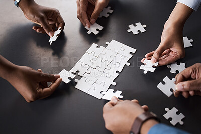 Buy stock photo Closeup shot of a group of unrecognisable businesspeople joining puzzle pieces together in an office