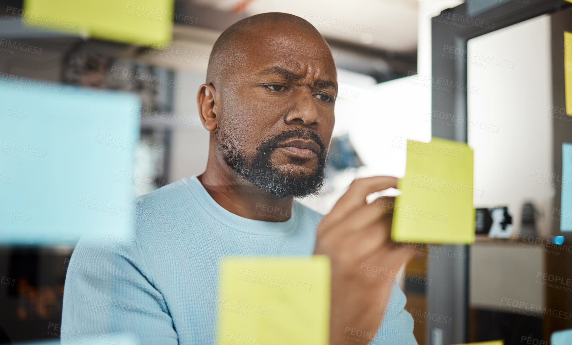 Buy stock photo Shot of a businessman brainstorming with sticky notes on a glass screen