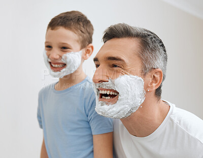 Buy stock photo Cropped shot of a handsome mature man teaching his young son how to shave in the bathroom at home