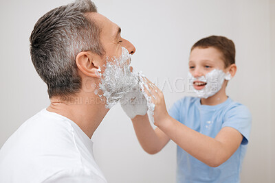 Buy stock photo Cropped shot of a handsome mature man teaching his young son how to shave in the bathroom at home