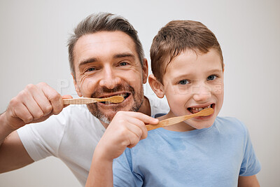 Buy stock photo Cropped portrait of a handsome mature man and his young son brushing their teeth in the bathroom at home