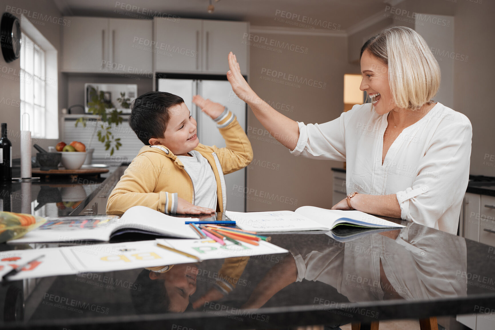 Buy stock photo Shot of a young mother and her son high fiving while home schooling