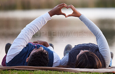 Buy stock photo Shot of a couple creating a heart shape with their hands during a camping trip