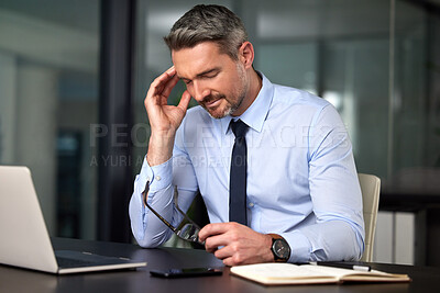 Buy stock photo Cropped shot of a handsome mature businessman suffering with a headache while working at his desk in the office